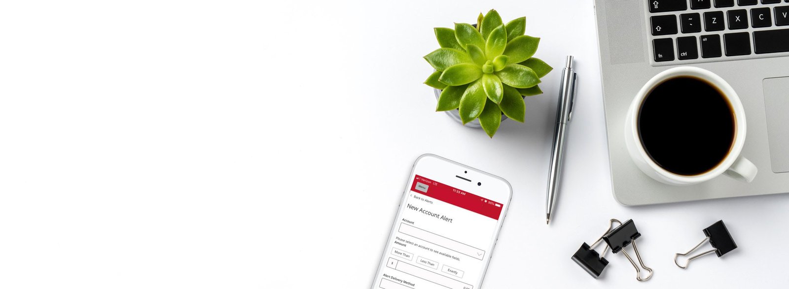Phone with lite Valley Credit Union app alerts screen, laptop on tabletop